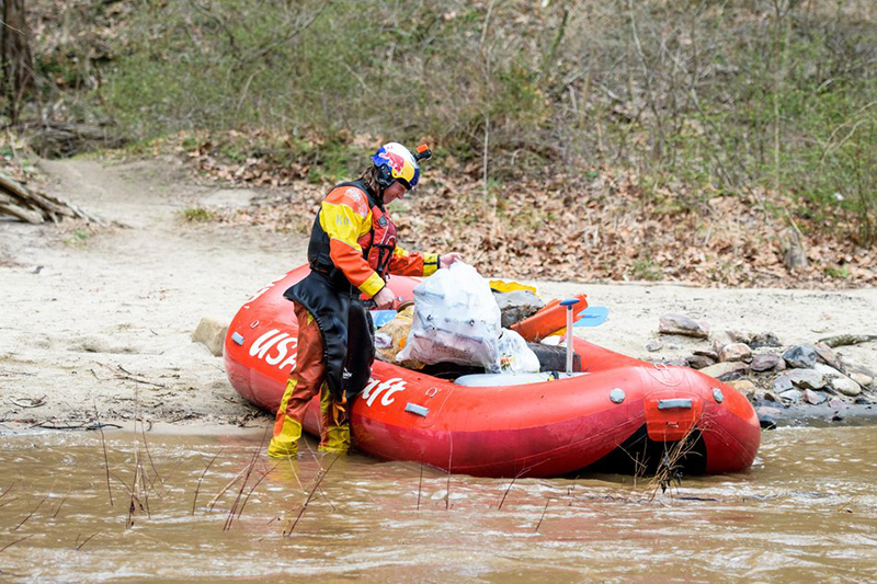 Dane Jackson ties up a garbage bag full of trash on the Nolichucky River.