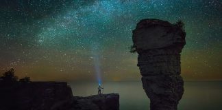 person gazing up at a sea of stars with a headlamp