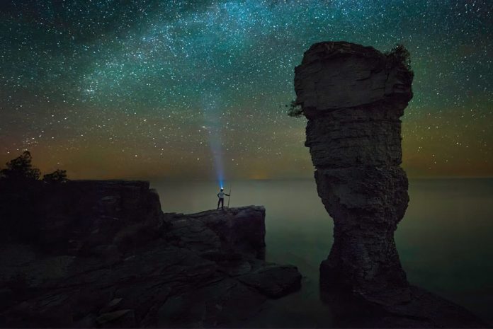 person gazing up at a sea of stars with a headlamp