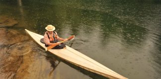 Man paddling a long wooden canoe