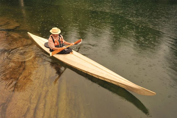 Man paddling a long wooden canoe