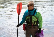 man holding a kayak paddle and wearing paddling gear