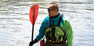 man holding a kayak paddle and wearing paddling gear