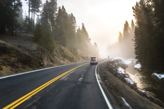 car driving down highway with kayaks