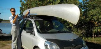 man standing next to his car with a canoe strapped on top