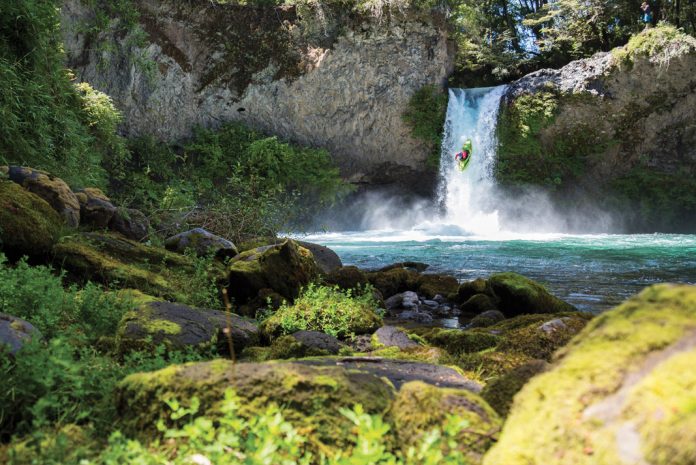 man kayaking off a waterfall