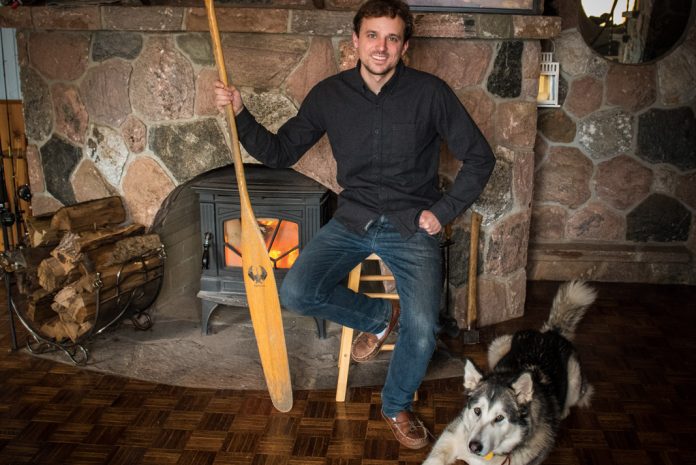 man holding a paddle and sitting with his husky dog