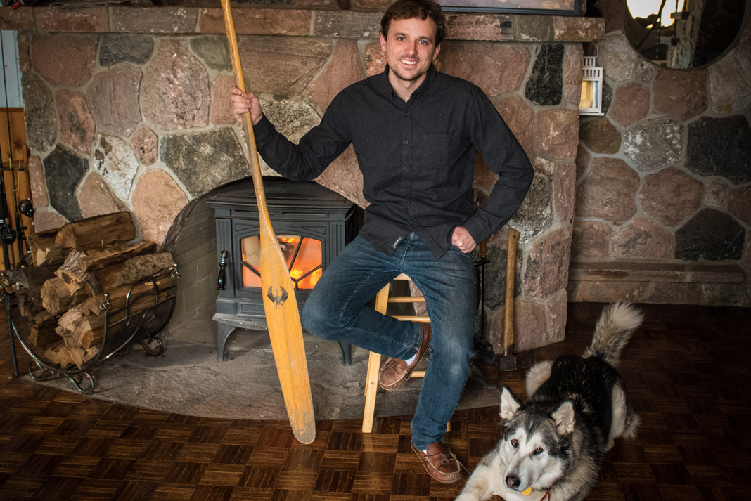 man holding a paddle and sitting with his husky dog
