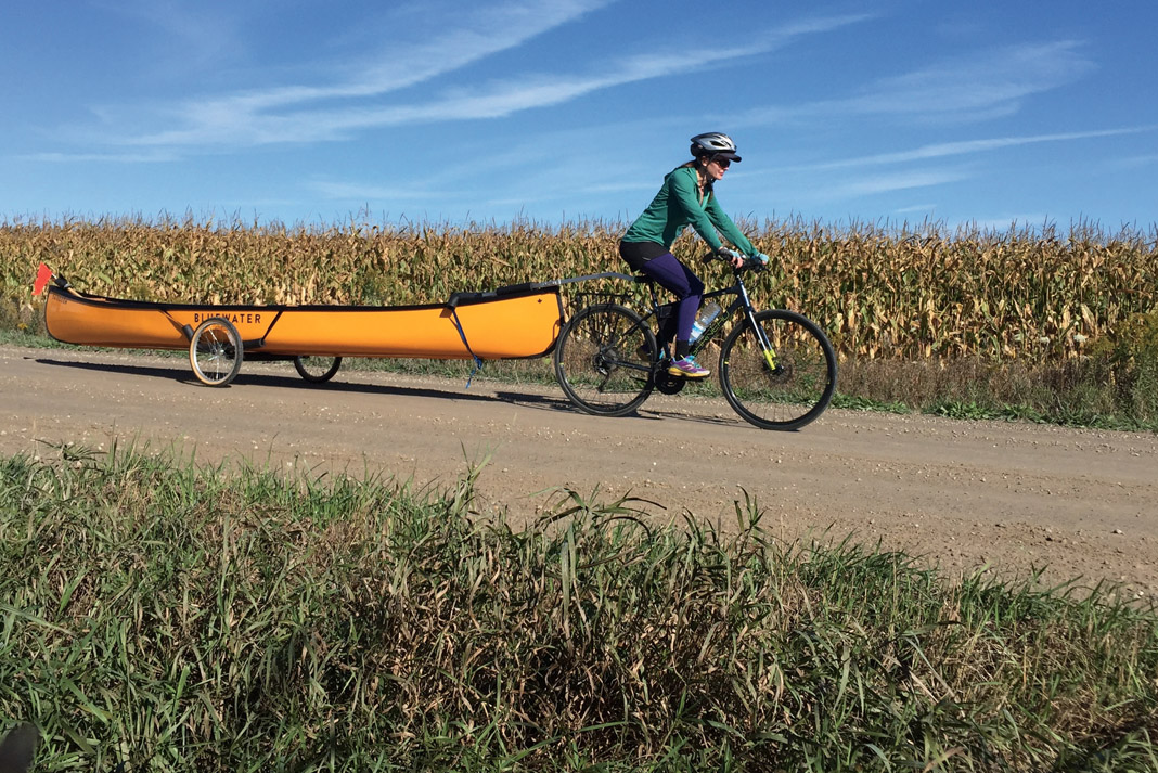 Woman on a bike shuttling a Bluewater Saugeen canoe