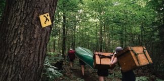 paddlers carrying gear on a portage trail