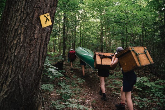 paddlers carrying gear on a portage trail