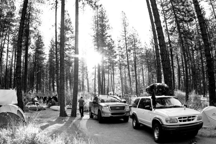 several trucks with kayaks on top surrounded by paddlers