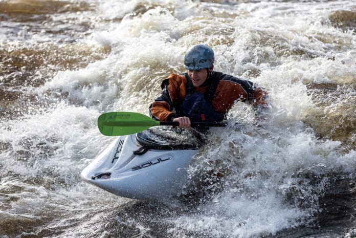kayaker surfing wave in the main squeeze boat