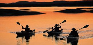 three paddlers kayaking in the sunset light