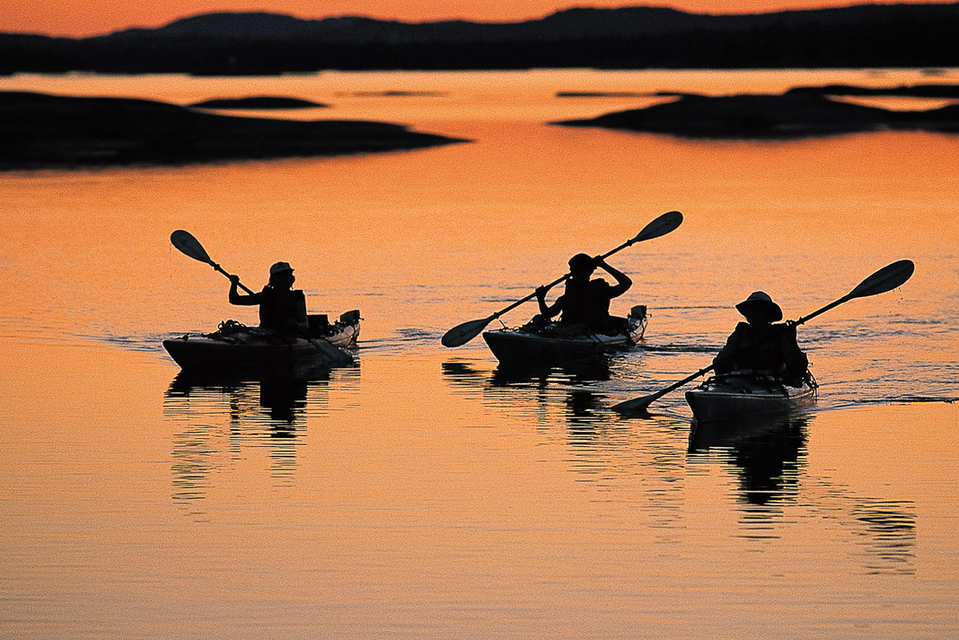 three paddlers kayaking in the sunset light