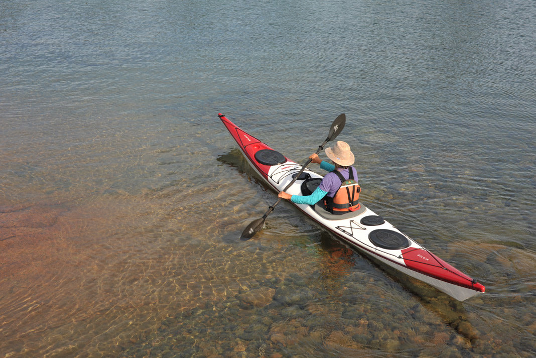 person paddling a red and white norse kayak