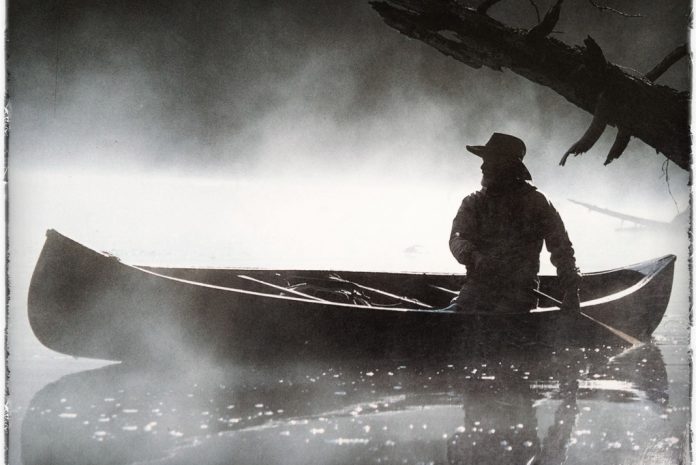 Bill Mason paddles in a canoe in black and white
