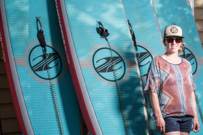 Brenna Kelly standing in front of paddle boards