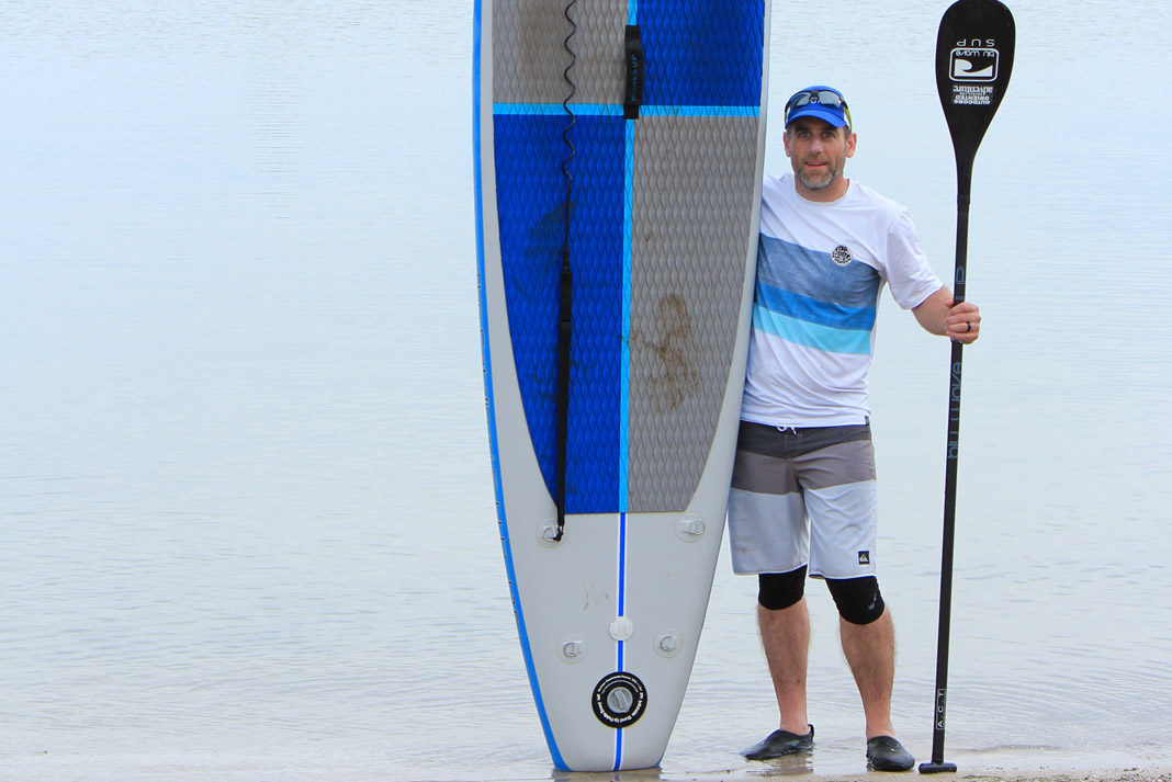 Dan Dakin holding up a paddleboard and paddle