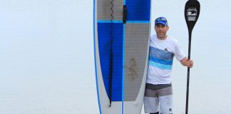 Dan Dakin holding up a paddleboard and paddle