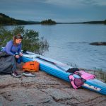 8 Essentials For SUP Expedition Racing woman surrounded by paddlboarding gear