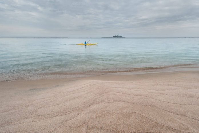 man paddling in the distance from a beach