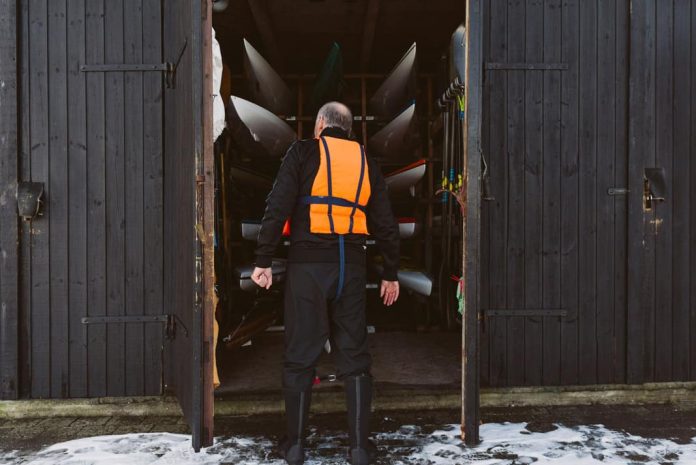 man wearing an orange pfd looking at boats