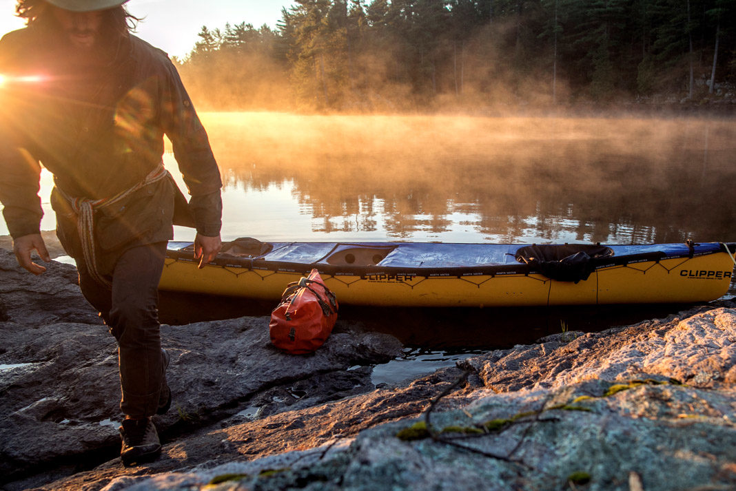 David Jackong walking away from his yellow canoe beside a lake in Canada
