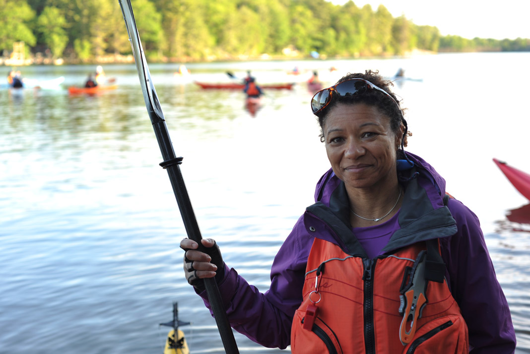 woman holding a paddle in from of a lake
