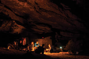 group of people sitting by fire in cave