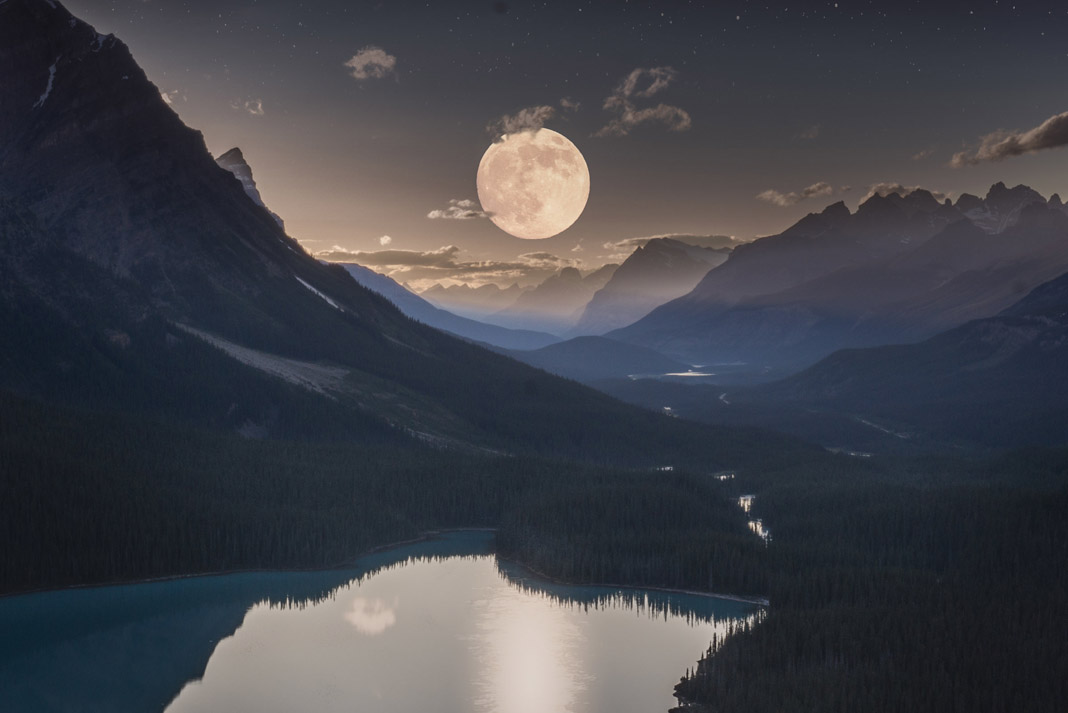 full moon over mountains and a lake
