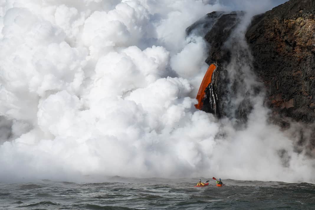 lava pouring out of a volcano into the river causing lots of steam
