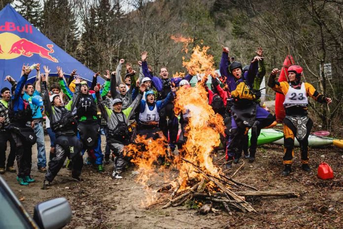 A group of kayakers pose in front of a bonfire at a kayak festival