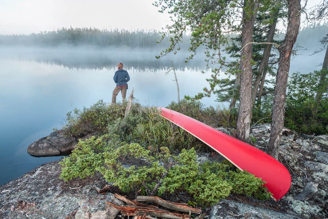 man standing on an island with a canoe
