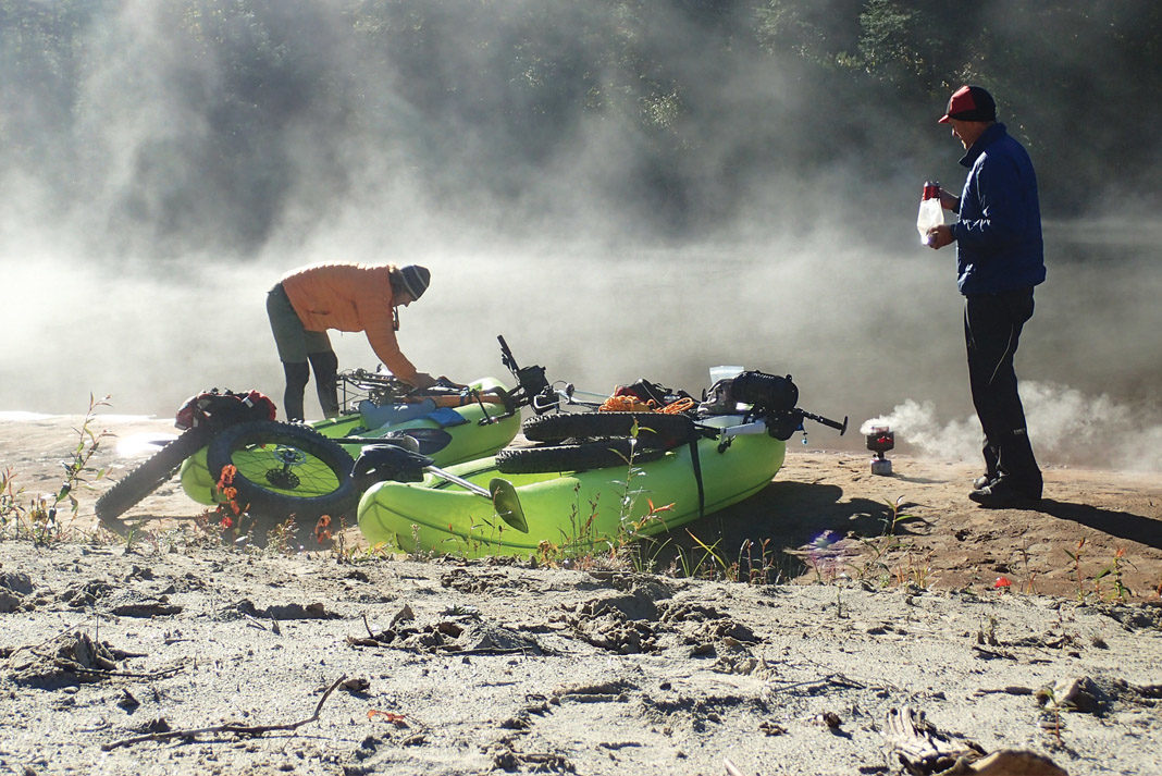 Two men load bikes into an inflatable packraft