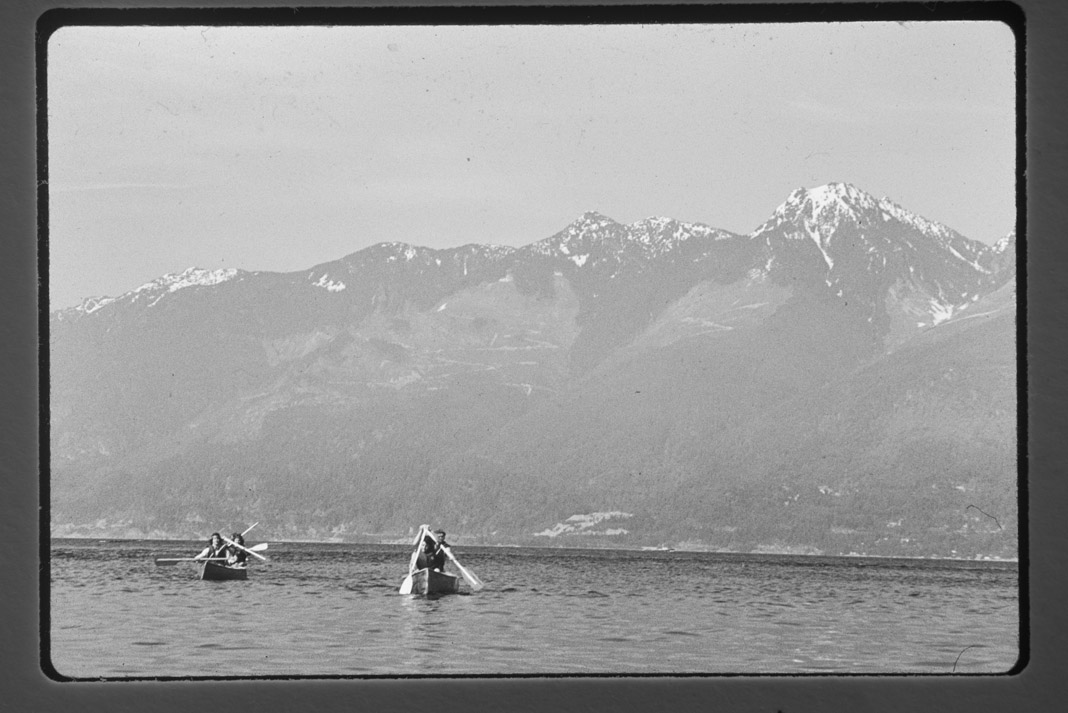 canoes paddling in the distance with mountains in the background