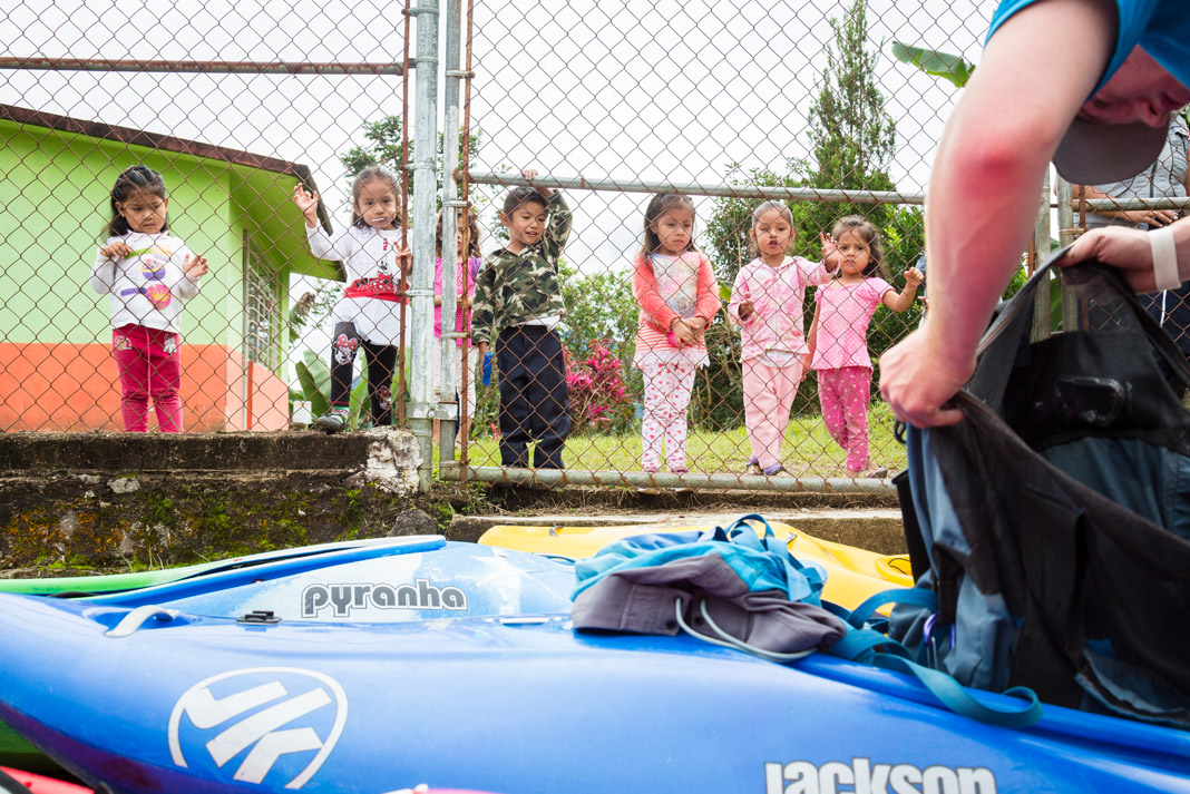 children looking at a man with his kayak