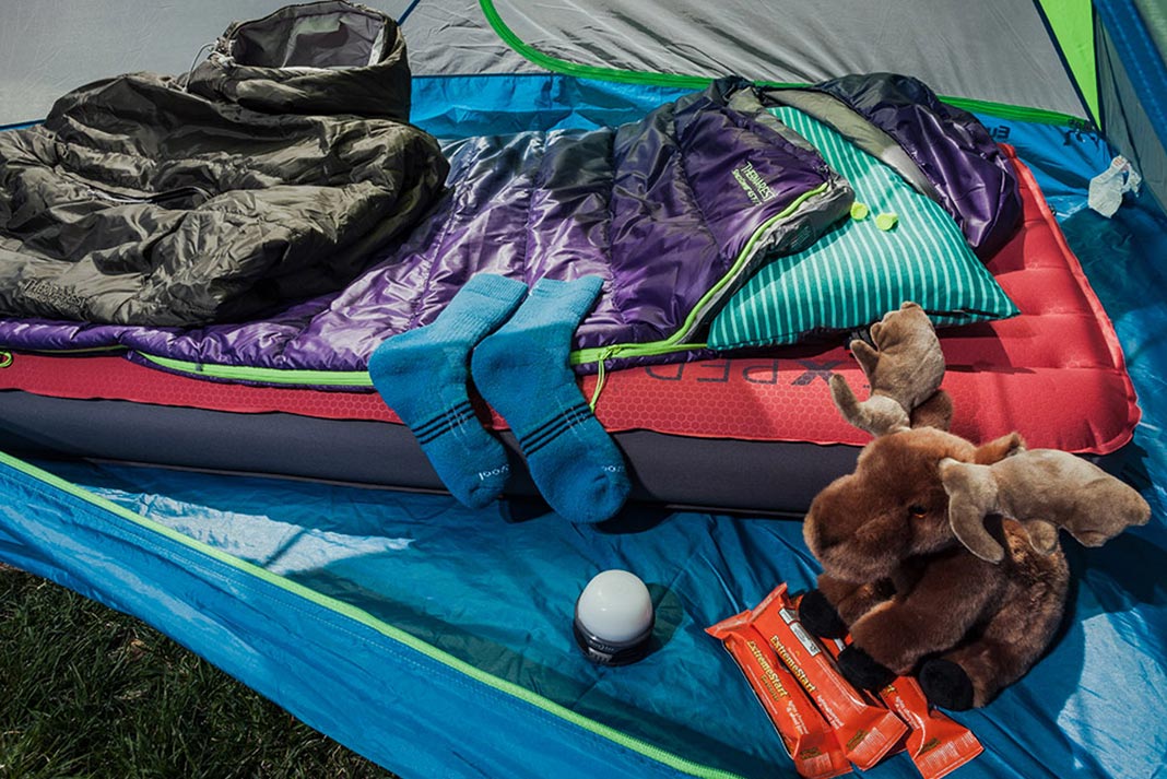 Socks, poncho, sleeping pad, sleeping bag, and other gear laid out on floor of tent