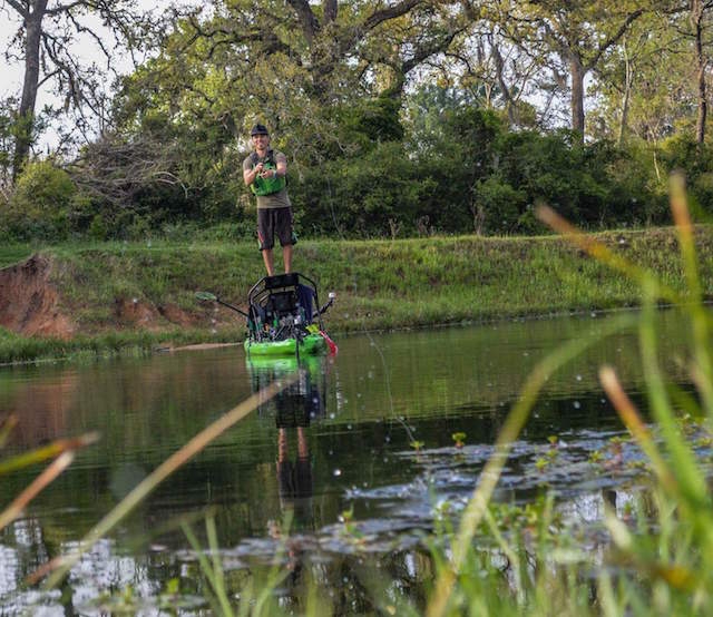 A kayak angler stands up on his fishing kayak as he reels in his fishing line. Photo: Mark Vlaskamp
