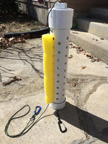 A capped white homemade bait tube stands with yellow foam attached to aid bouyancy.