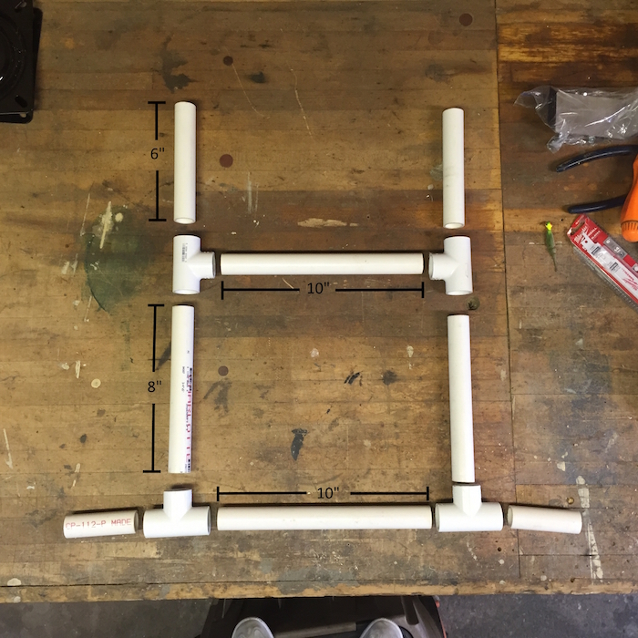 A layout on the floor of separate pieces of PVC pipe that outline the kayak cart.