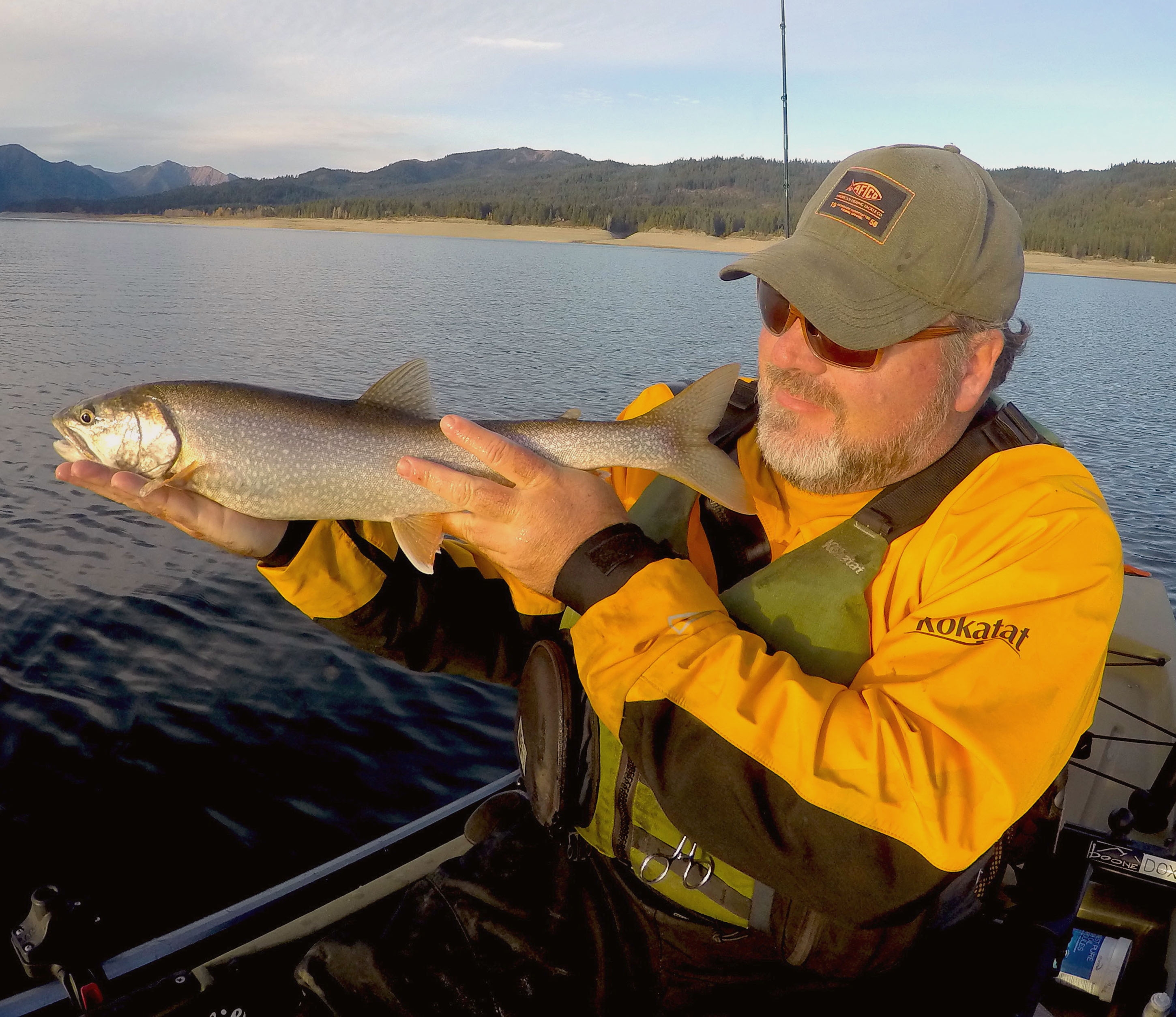 A man holding a trout in his kayak Photo By: Brad Hole