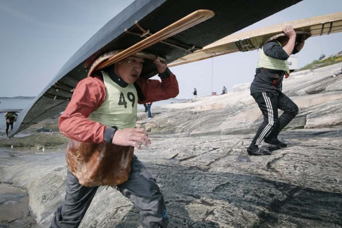 Karl Bjorn Hansen runs with his qajaq up the shoreline in the youth portage race.