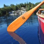 Why Your Canoe Paddle Choice Is So Important A canoeist paddling with a wooden canoe paddle on a lake