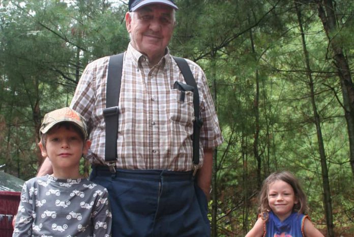 Harold Jessup standing with two children near the Madawasja River