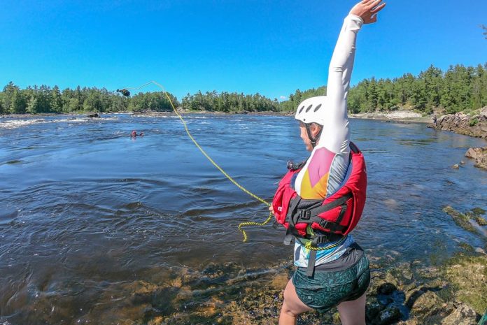 kayaker throwing a throw bag to a fellow paddler swimming in the water