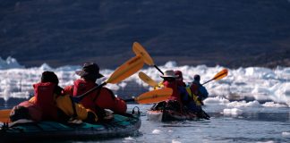 several kayakers paddling Feathercraft kayaks in amongst ice in the Arctic