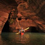 Kayaker paddles through red caves