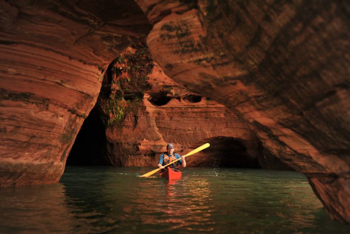 Kayaker paddles through red caves