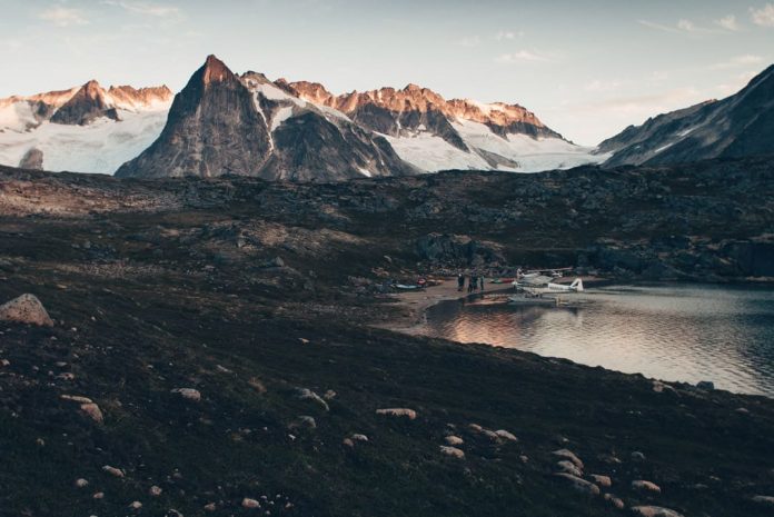 a plane sitting on a lake surrounded by mountains in Alaska